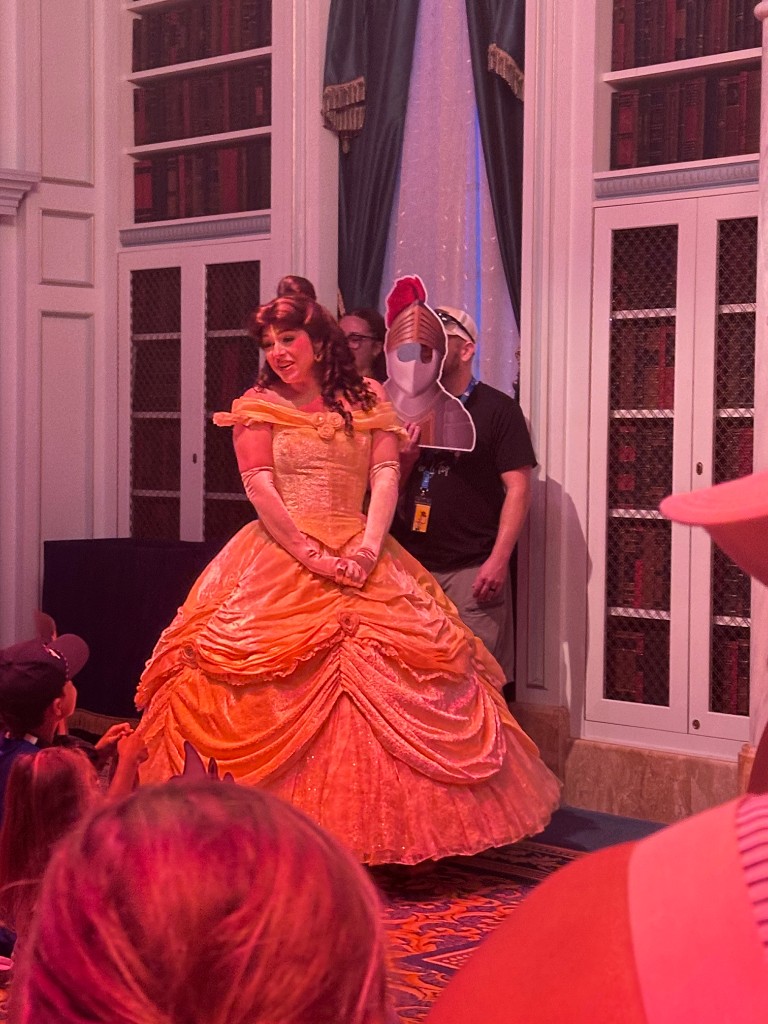 Belle in a gold gown with a child holding a knight cutout