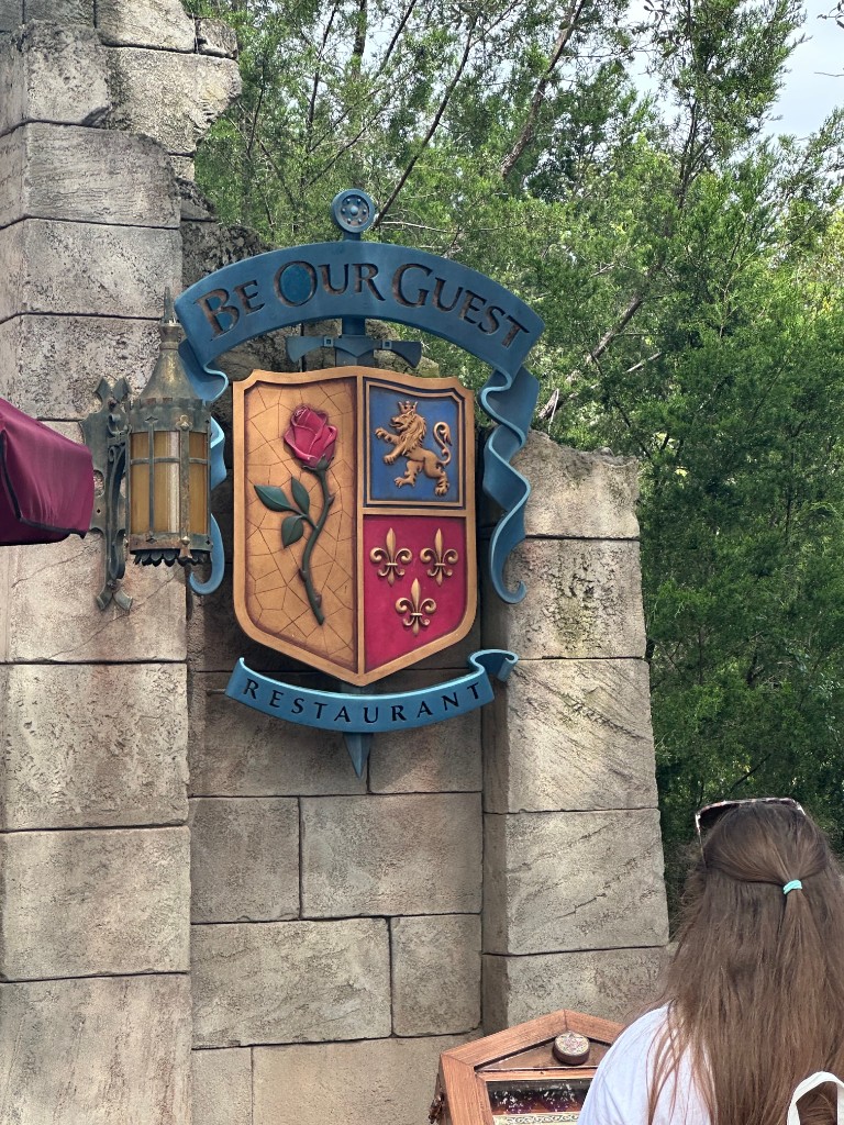 Be Our Guest Restaurant crest on the castle wall