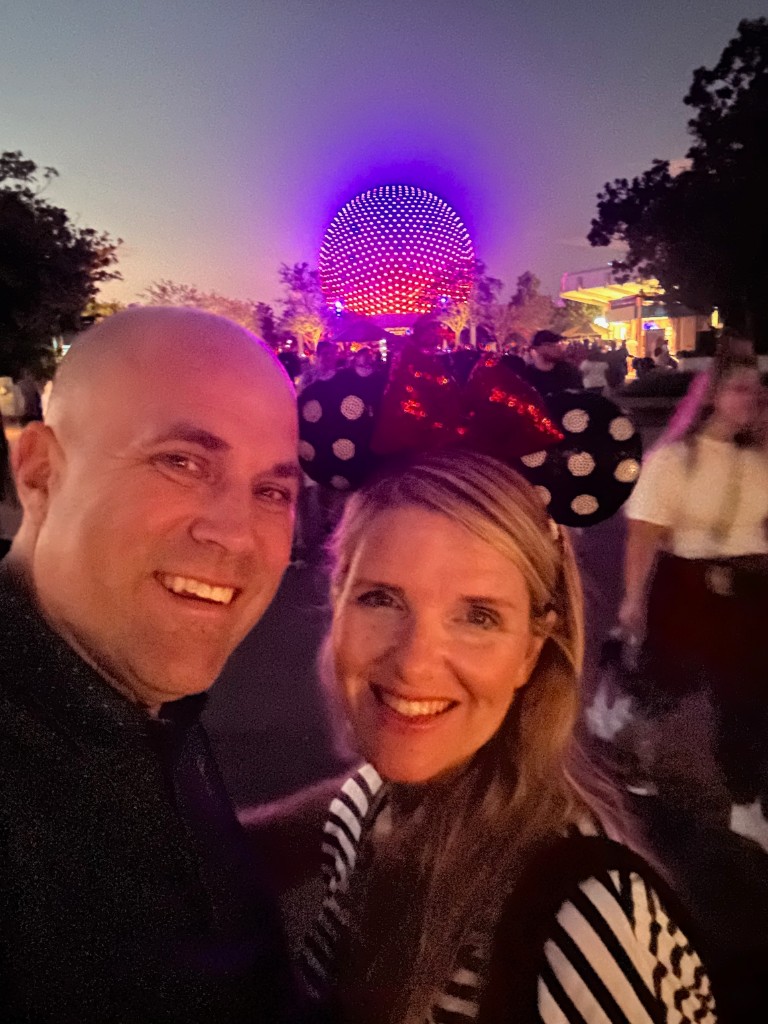 Ryan and Sarah with Spaceship Earth lit purple at night