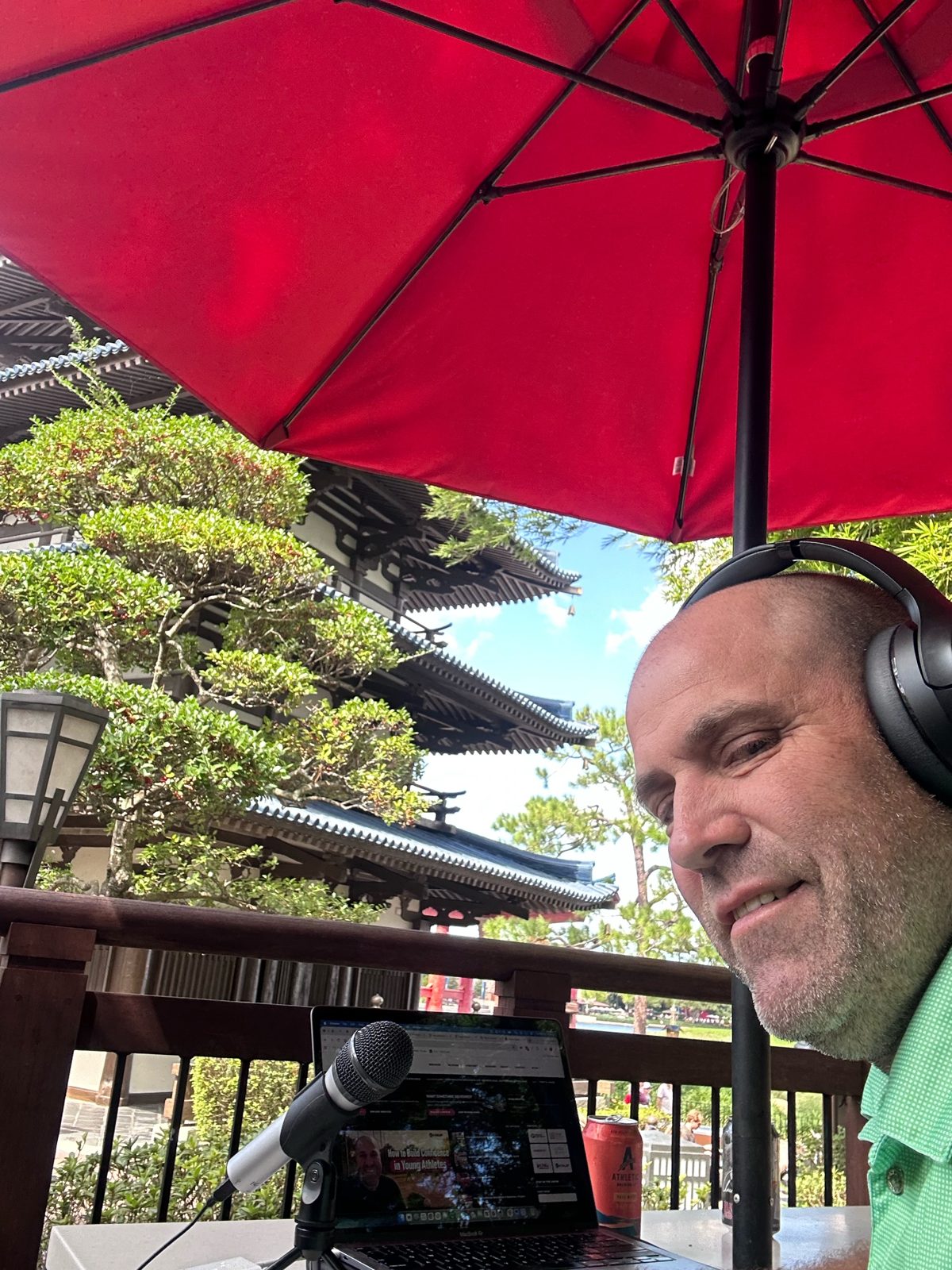 Ryan in headphones under a red umbrella at the Japan pavilion work spot