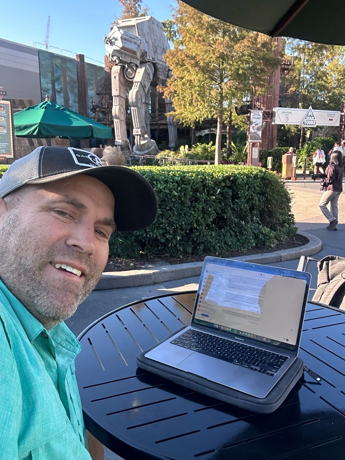 Ryan with his laptop at a table at Backlot Express, the AT-AT from Star Wars behind him