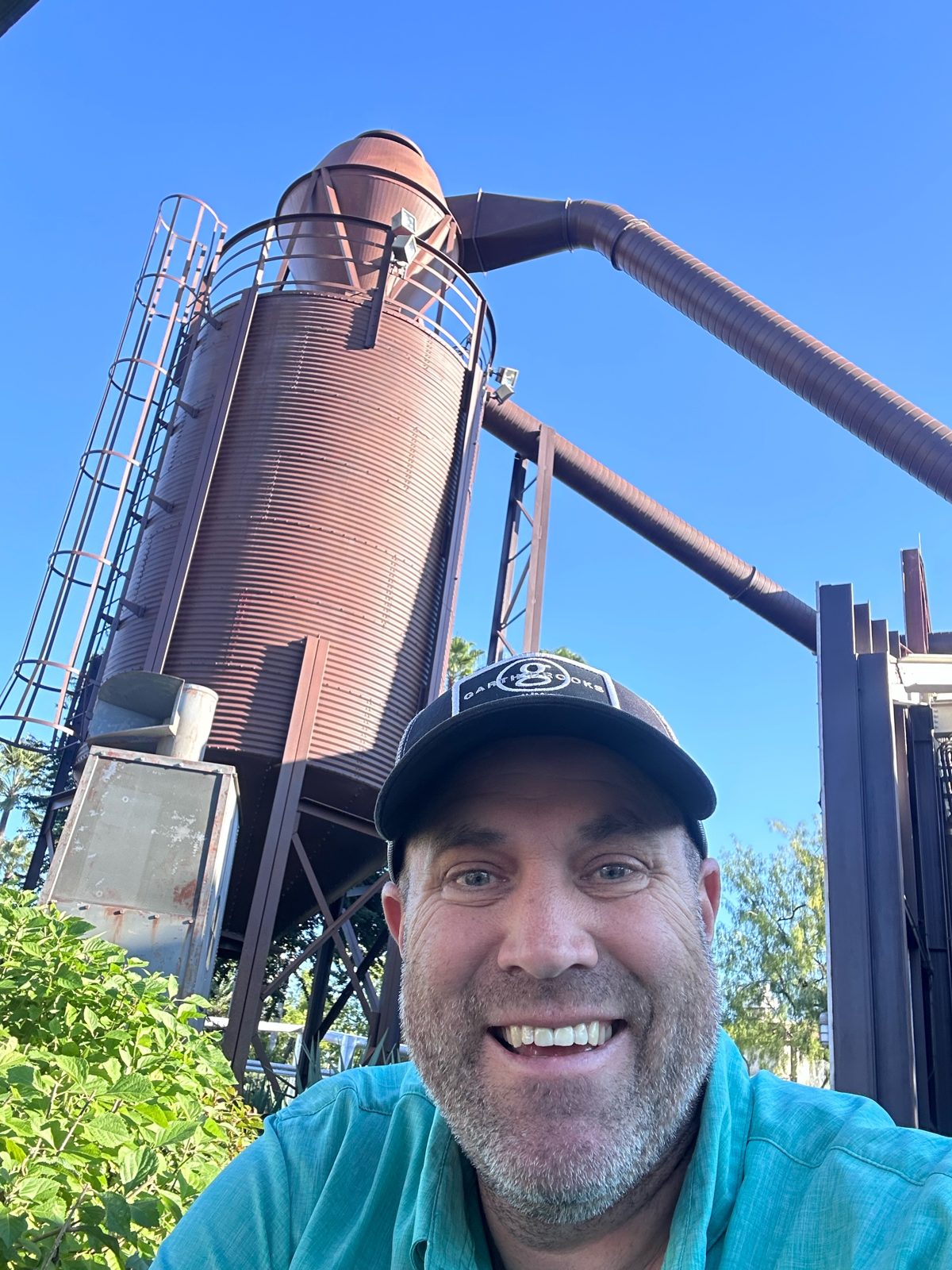Ryan smiling under the rusty silo tower at Hollywood Studios