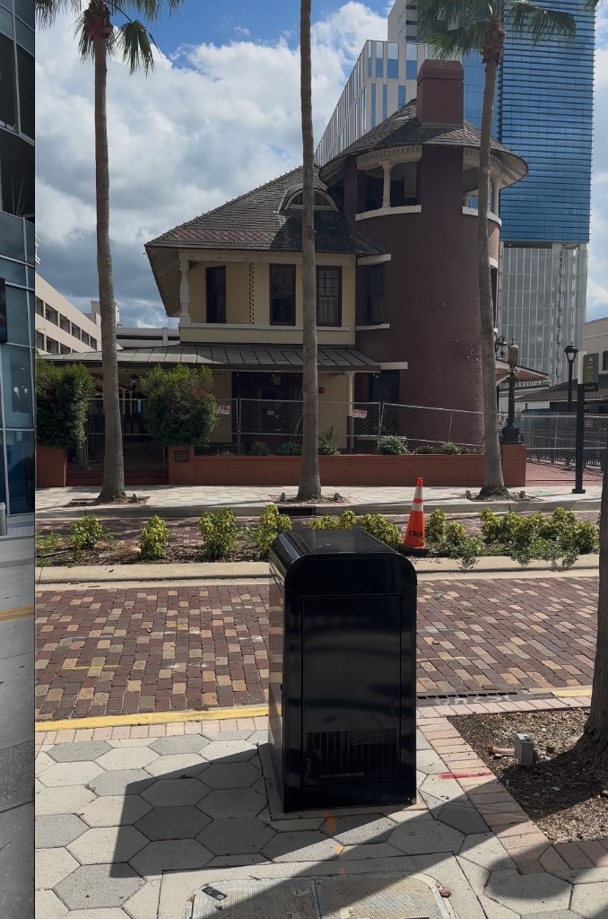 Historic building on brick street with downtown Orlando skyline behind it