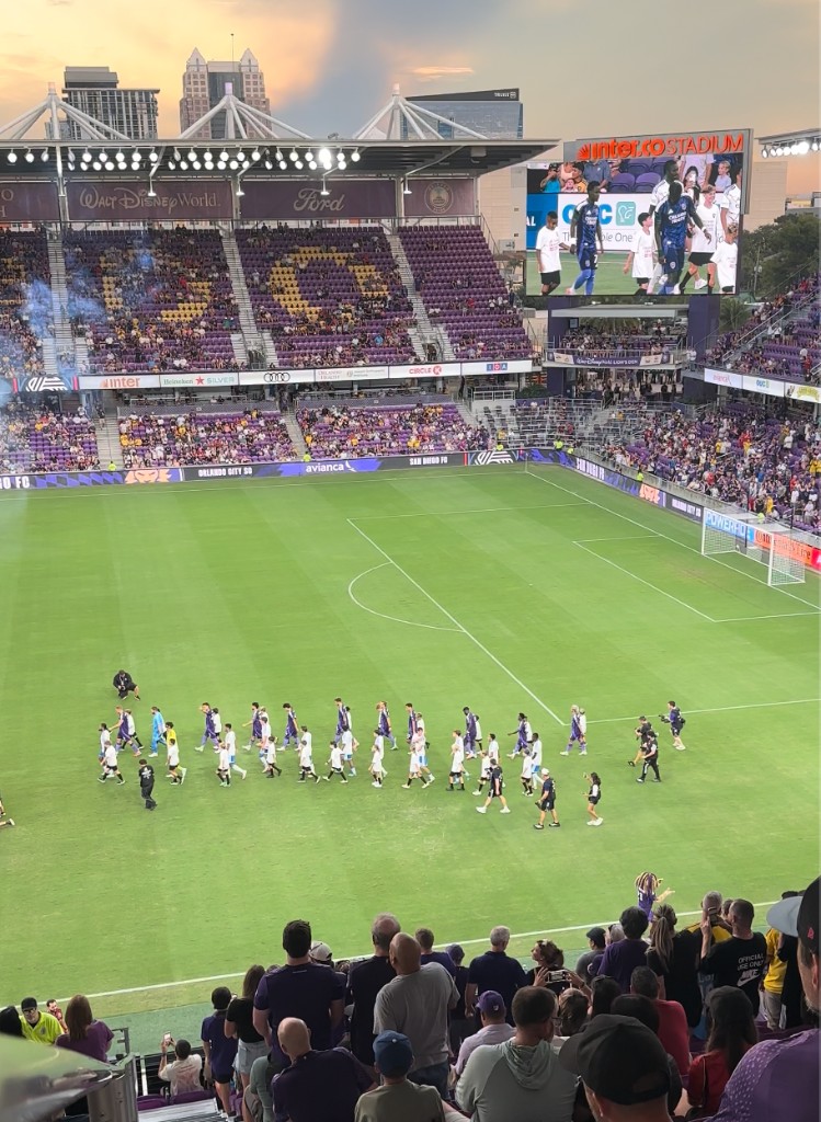 Teams walk out at dusk with Avianca boards