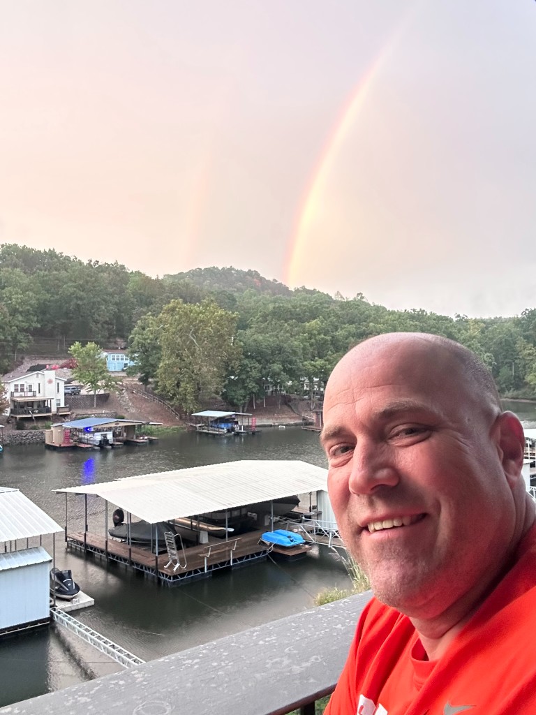Ryan on the deck with a rainbow over the cove