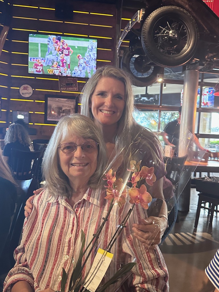 Sarah and her mom with birthday orchid under the upside-down Ford