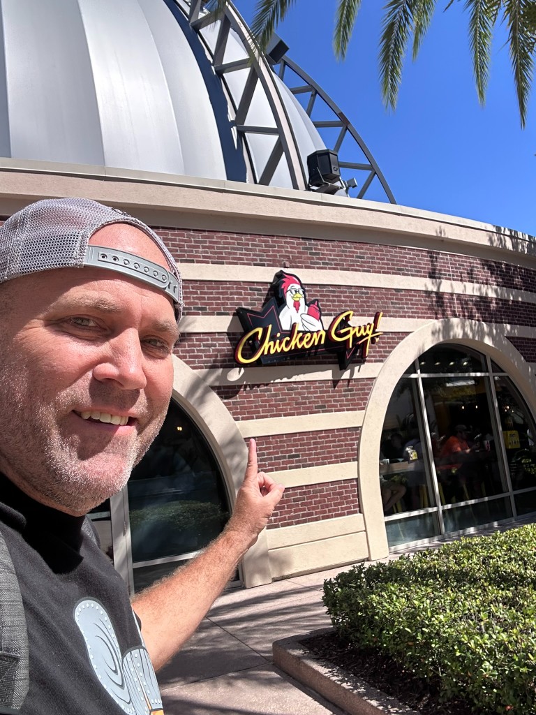 Ryan pointing at the Chicken Guy! sign at Disney Springs