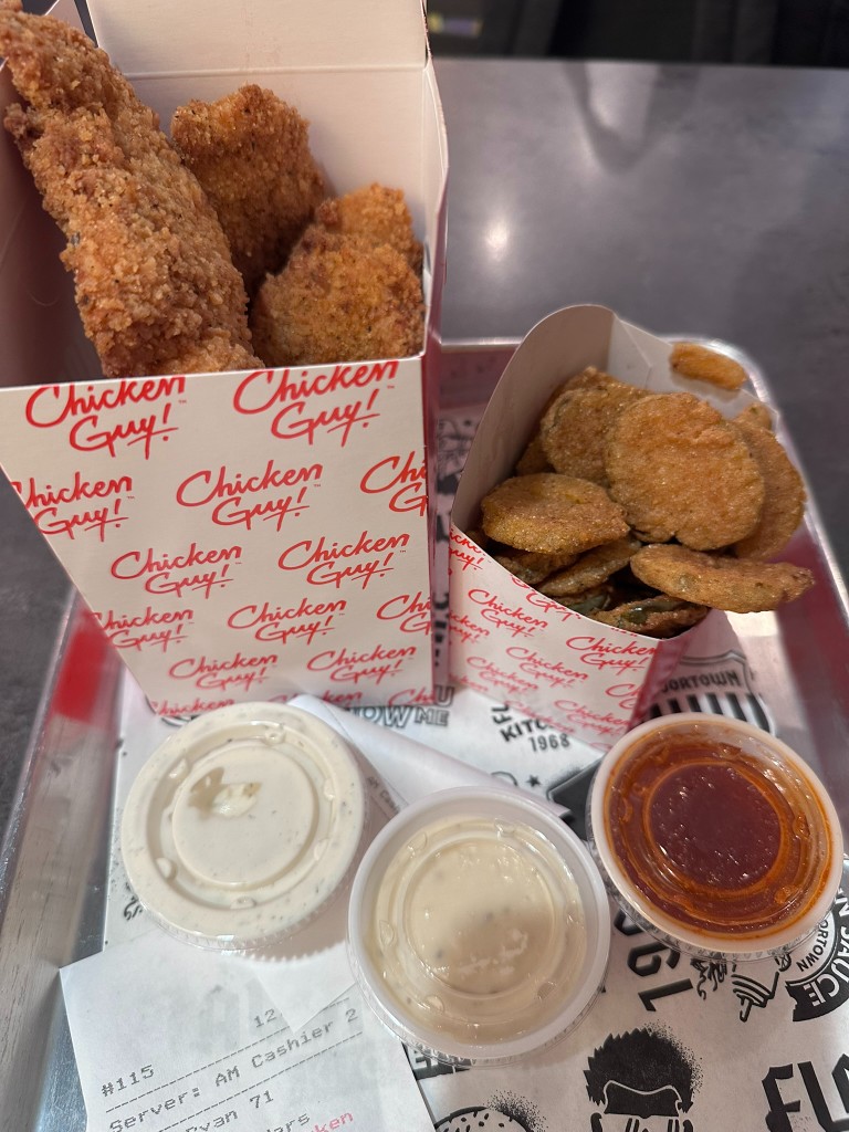 Tray of chicken tenders, fried pickle chips, and three dipping sauces