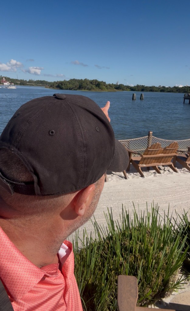 Ryan pointing across Seven Seas Lagoon toward Magic Kingdom from the Polynesian beach