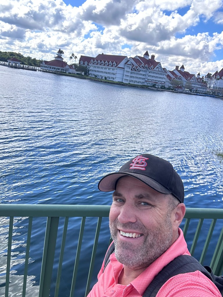 Ryan on the walkway with Grand Floridian across the lagoon