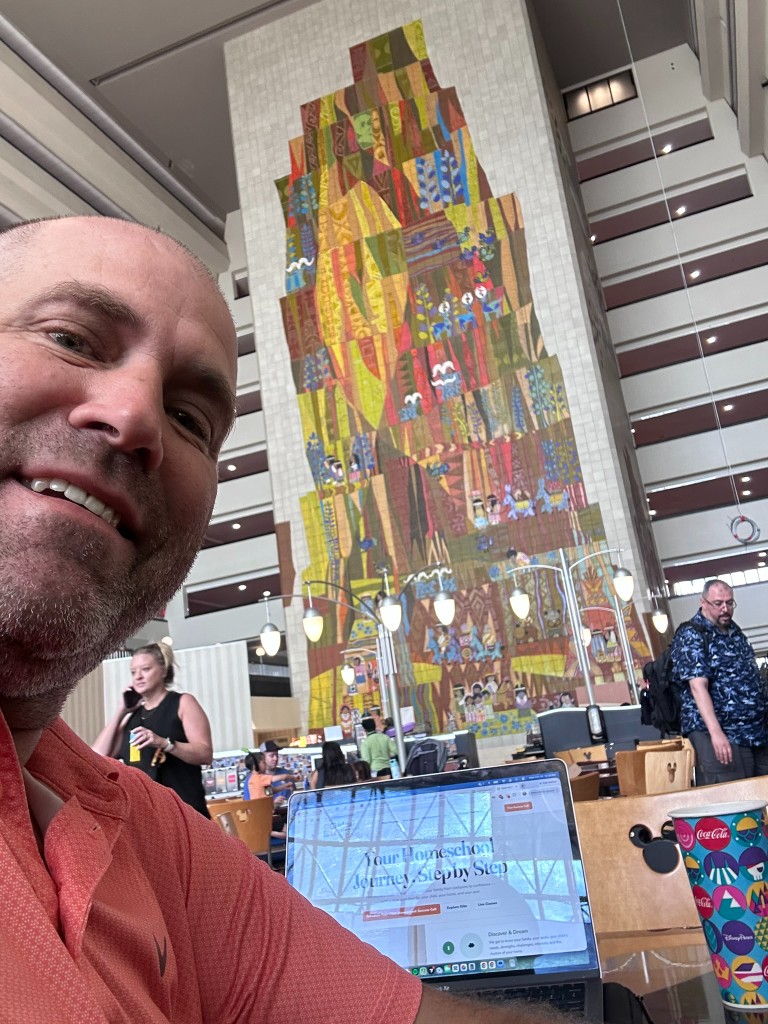 Ryan working on a laptop in the Grand Canyon Concourse by the Mary Blair mosaic