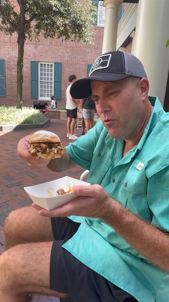 Ryan holding the Smoked Brisket and Cheddar Melt at American Adventure
