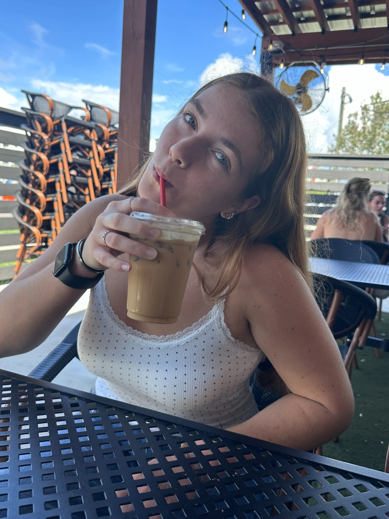 Alyssa with an iced coffee on the outdoor patio