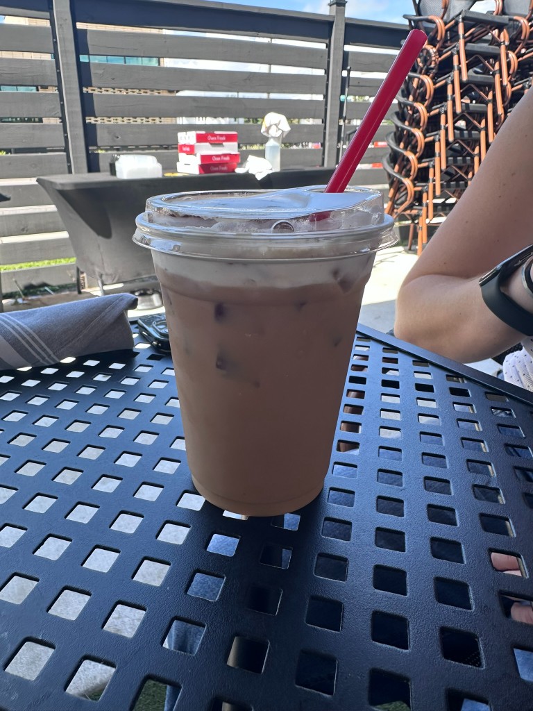 Iced coffee with a red straw on the metal patio table