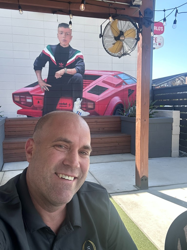 Ryan on the patio in front of the car mural