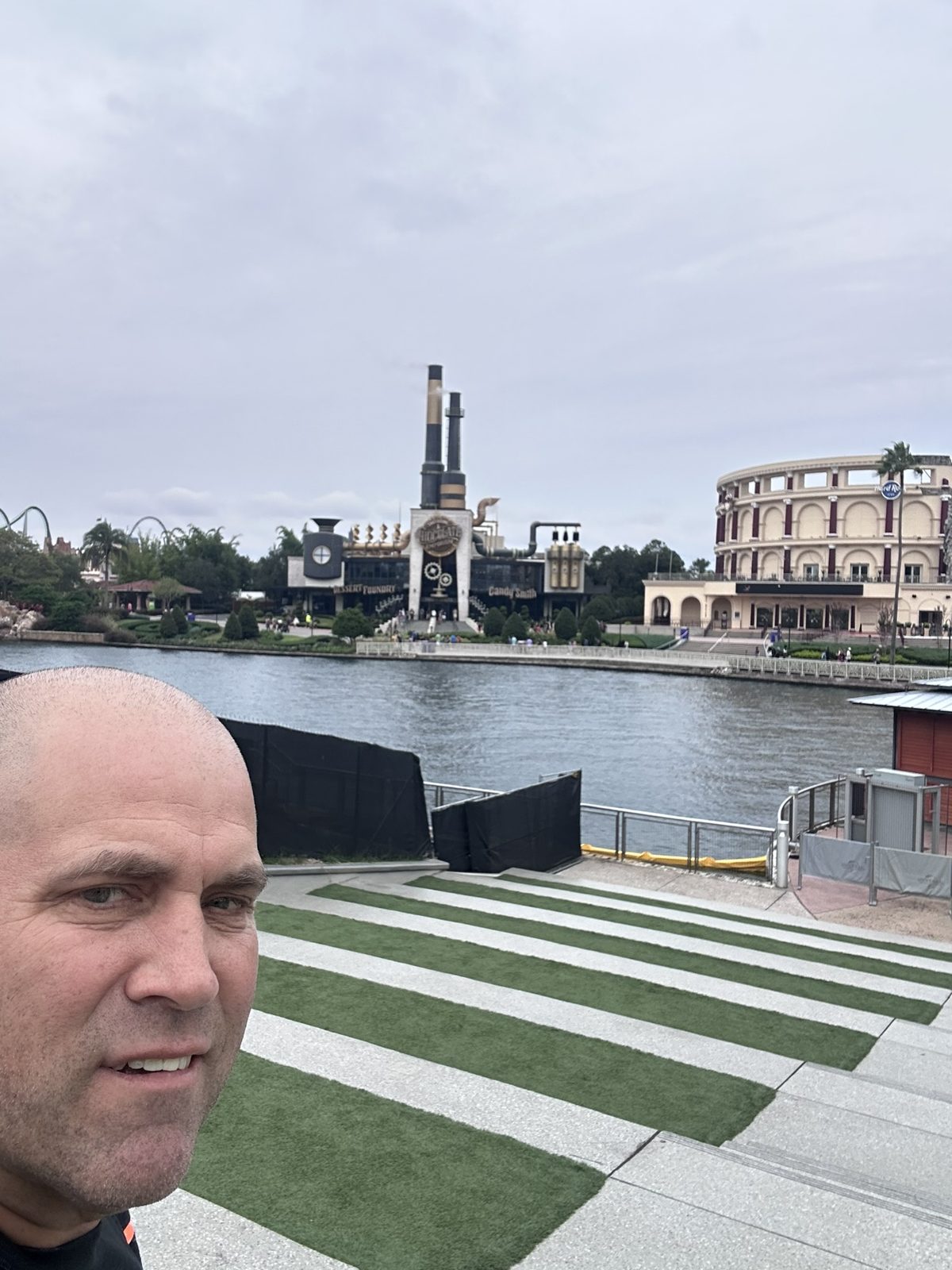 Ryan taking a selfie on the CityWalk waterfront steps, with Toothsome Chocolate Emporium and Hard Rock Cafe across the water