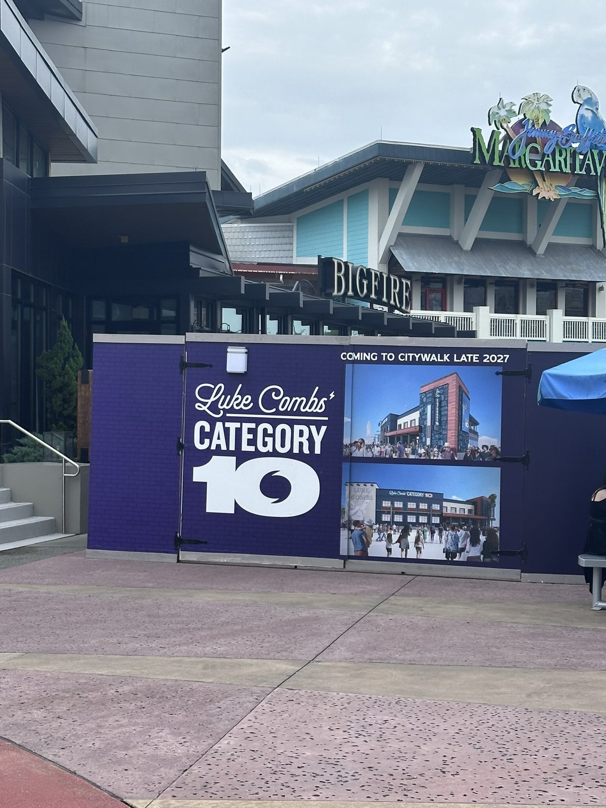 Luke Combs' Category 10 construction wall with renderings and a Coming to CityWalk Late 2027 banner, Bigfire and Margaritaville behind