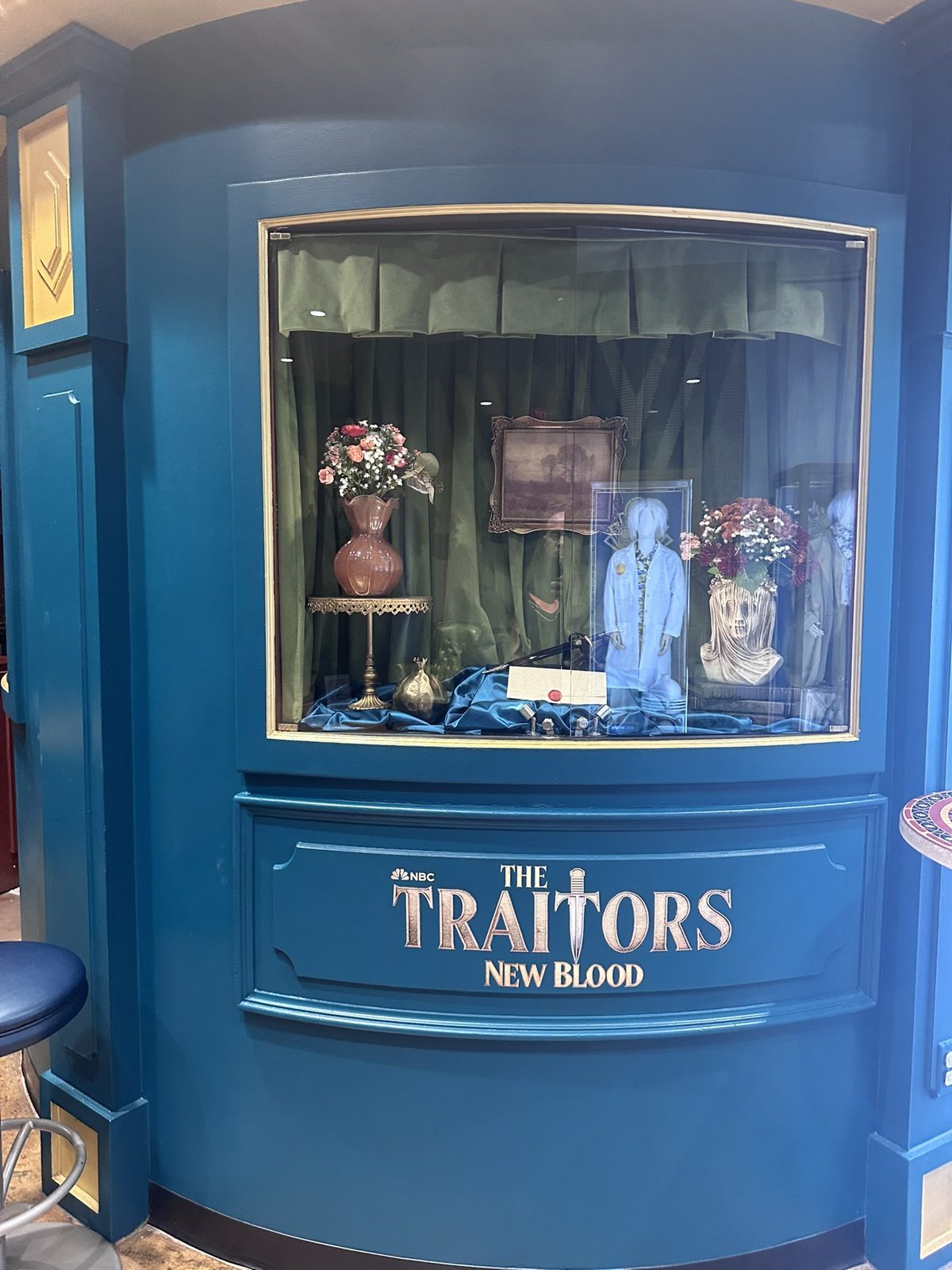 The Traitors: New Blood display case with props, flowers and a sealed envelope